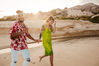 A couple holds hands running on a sandy beach at Marquis Los Cabos in Mexico